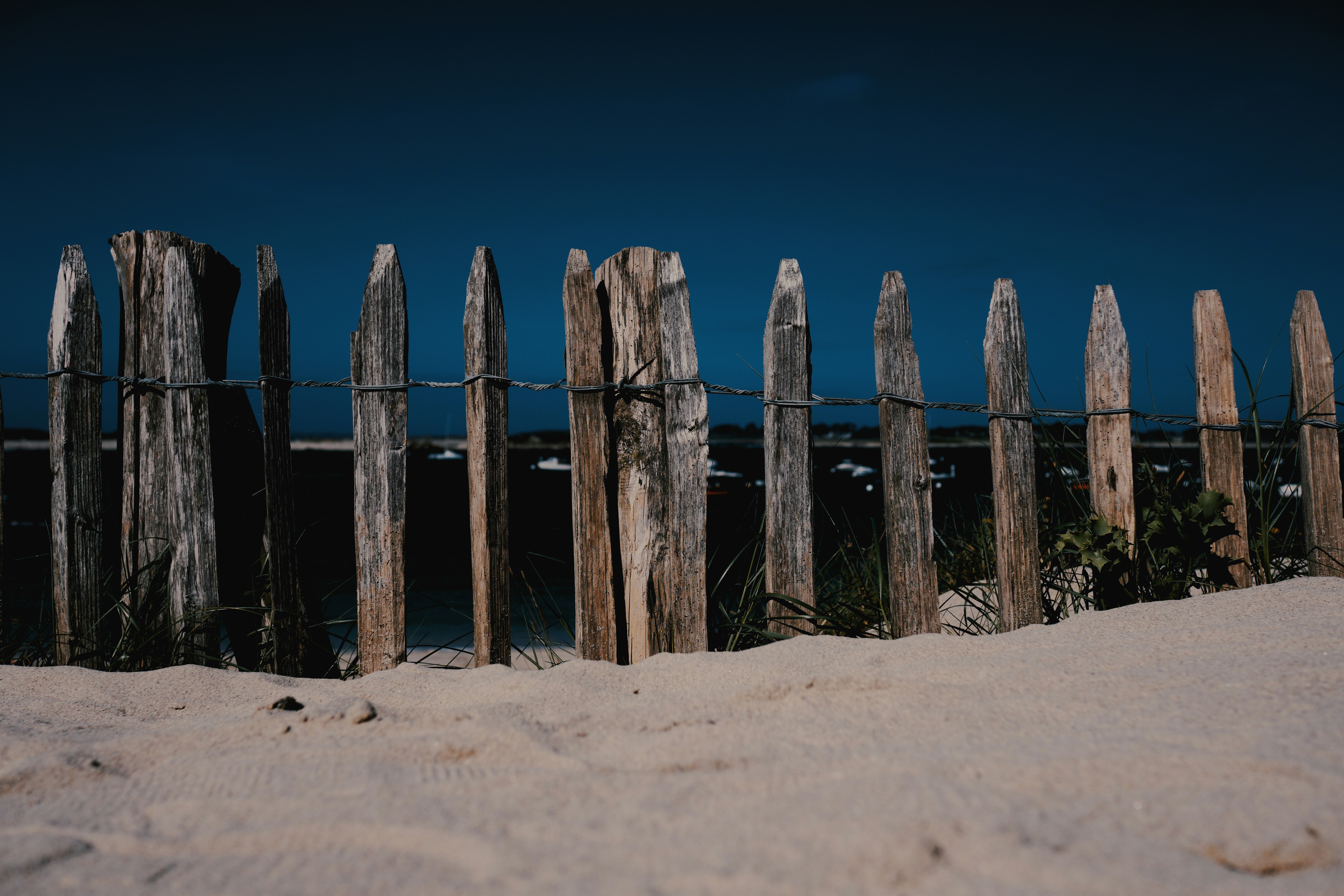 brown wooden fence on brown sand under blue sky during daytime